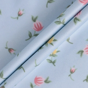 Detailed macro shot of floral print fabric with pink tulips on soft blue texture