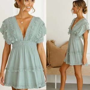 Détail de robe verte à pois avec décolleté en V, bordure en dentelle et pompons