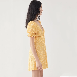 Detail of yellow floral V-neck mini dress with puff sleeves and button front design