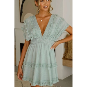 Détail de la robe en dentelle vert menthe avec col en V, glands et ourlet à plusieurs niveaux