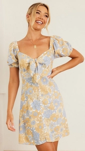 Détail de mini robe fleurie avec décolleté en cœur et détail de nœud sur la poitrine