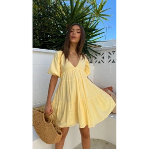 Elegant pale yellow V-neck dress with puff sleeves and tiered skirt for summer outdoor wear