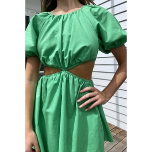 Dettaglio delle maniche a sbuffo e del design cutout in vita di un abito estivo verde a trapezio