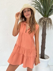 Detail of coral orange sleeveless tiered dress with V-neckline and drawstring detail