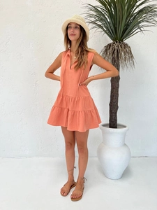 Detail of coral orange V-neck tiered mini dress in breathable textured cotton fabric