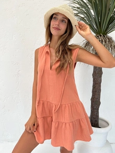 Detail of coral sleeveless V-neck dress with ruffled hem and lightweight fabric texture