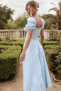 Detail of light blue floral dress with puff sleeves and square neckline in a garden