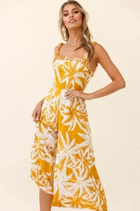 Detail of ruffled shoulder straps and white palm leaf print on yellow jumpsuit