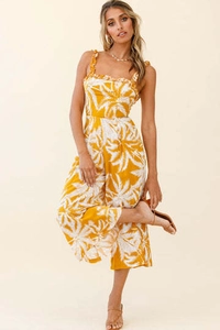 Detail of ruffled shoulder straps and white palm leaf print on yellow jumpsuit