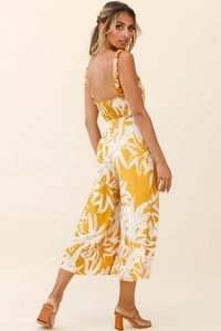 Detail of bohemian yellow jumpsuit with white palm print and ruffled shoulder straps