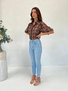 Full view of women's brown plaid short-sleeve shirt and high-waist jeans on a model