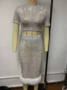 Dettaglio del top di paillettes e gonna aderente con decorazione di piume bianche