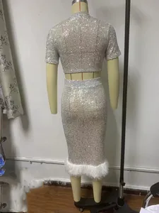 Dettaglio del crop top di paillettes argento e gonna a matita con bordo di piume