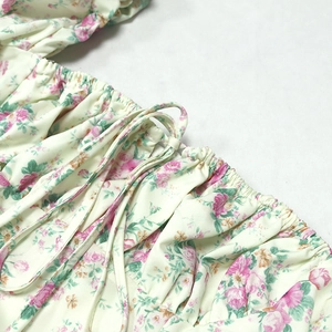 Close-up of floral print dress featuring elastic smocked details and slim drawstring ties