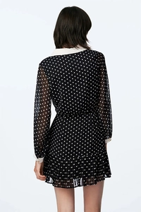 Rear view of long sleeve black polka dot chiffon dress with pleated skirt and white collar
