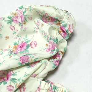 Close-up of pink rose floral print on yellow fabric with elastic ruffled smocking details