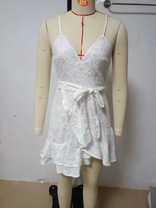 Detail of white lace dress with deep V-neck, waist bow tie, and delicate floral patterns