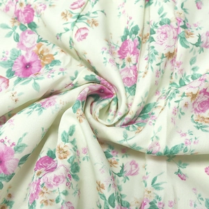 Close-up of floral print fabric with pink roses and green leaves on cream base