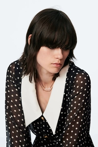 Detailed view of layered pearl necklace paired with a vintage polka dot dress collar