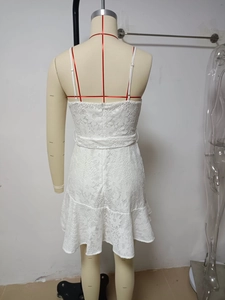 Detailed back view of white lace mini dress with ruffle hem and delicate floral patterns
