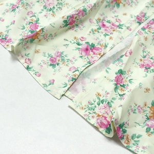 Detail view of the floral print pattern and split hem on the yellow summer tea dress