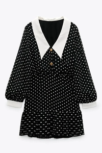Macro detail of retro polka dot chiffon dress featuring white pointed collar and gold buttons