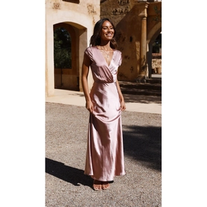 Gros plan du décolleté en V profond et de la texture satinée sur la robe longue rose