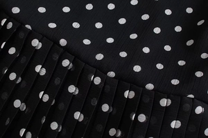 Detailed macro view of black polka dot chiffon fabric with elegant pleated texture