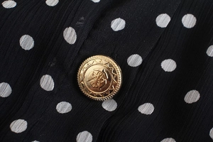 Close-up of vintage gold embossed button on black and white polka dot chiffon dress