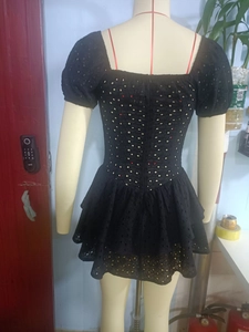 Detail of black lace dress showing intricate hollow embroidery and ruffled cake skirt layers