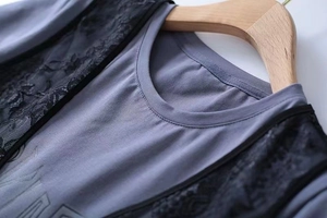 Detail of round neck T-shirt with black lace patchwork and letter print on gray fabric