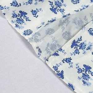 Detailed view of the blue floral print on white fabric and quality hem stitching