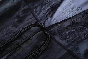 Detail of vintage black lace vest featuring traditional knot tie and textured fabric