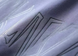 Detail of geometric pattern printing on purple knitted fabric with texture