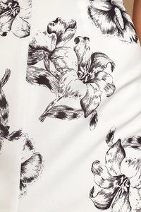 Close-up of the ivory fabric with black lily floral prints and LULUS brand label