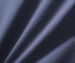 Detailed close-up of dark blue knitted fabric texture with soft waves and fine weave