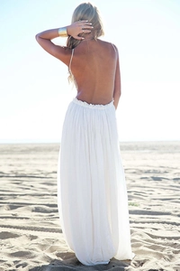 Dettaglio di un vestito lungo premaman bianco bohémien con schiena scoperta in spiaggia