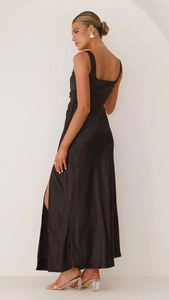 Detail of elegant black satin maxi dress with side slit and backless silhouette
