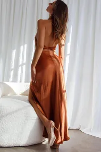 Detail of copper halter neck satin dress featuring backless twist and high side slit