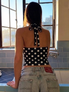 Polka dot halter backless top paired with light blue washed denim jeans for a chic look