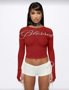 Dettaglio della stampa Blessed sul top corto a maniche lunghe rosso per donna