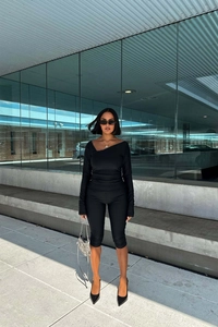 Close-up of black two-piece set featuring asymmetrical neck top and slim-fit shorts