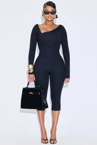 Detail view of black asymmetric neck jumpsuit with slim fit long sleeves and cropped pants