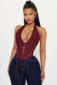 Detailed close-up of dark red halter corset top with metal eyelets and lace-up design