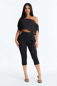 Detail of off-shoulder polka dot top with matching belt and black cropped leggings
