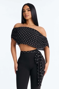Detail of off-shoulder polka dot chiffon top and black pants with matching waist tie