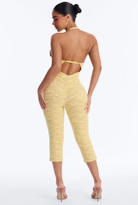 Back view of a yellow floral lace halter neck jumpsuit with an open back design