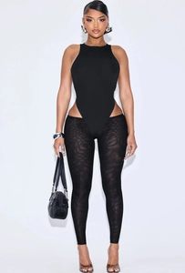 Detail von schwarzem Halter-Bodysuit mit transparenter Mesh-Leggings und silbernem Schmuck