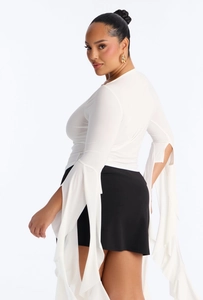 Détail du haut grande taille blanc avec manches fendues en cloche et texture de tissu fluide