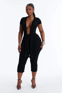 Detail of a chic black short sleeve jumpsuit featuring a deep V-neck and a waist tie-up
